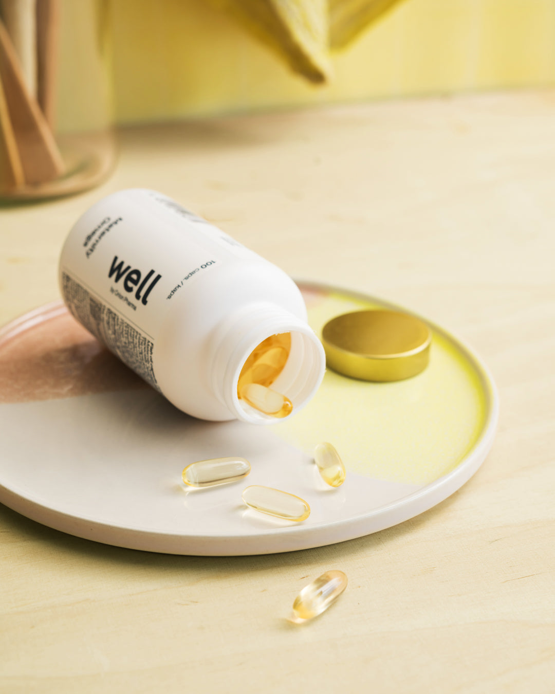 Open bottle of supplements labeled 'well' with capsules on a light surface.