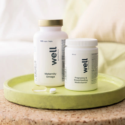 Two white supplement bottles labeled 'well' on a green tray with a neutral background