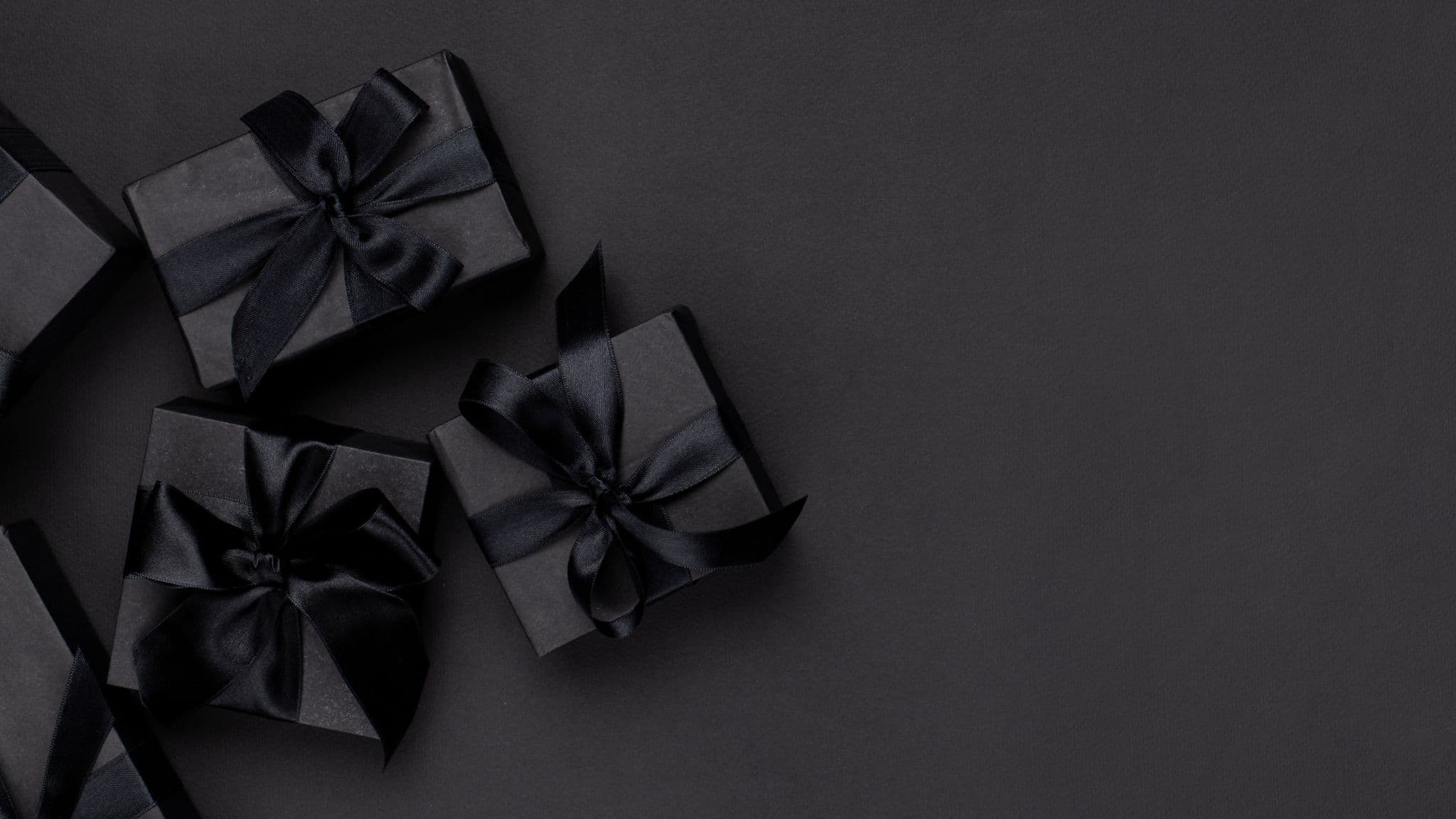 Black gift boxes with ribbons on a dark background