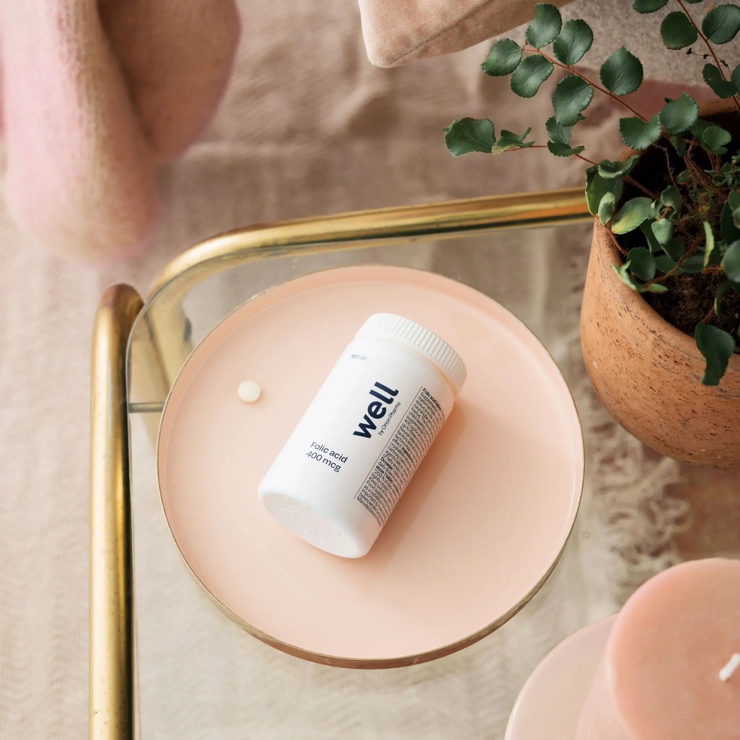 White container labeled 'well' on a pink surface with a plant in the background