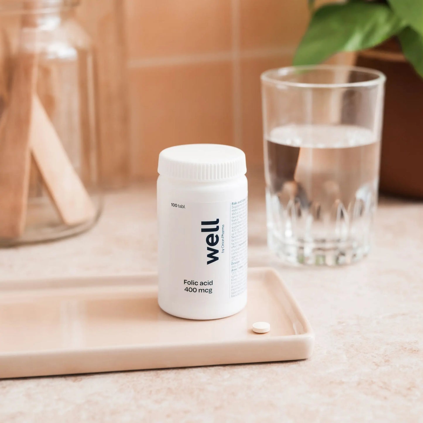 Well brand supplement bottle with a glass of water on a wooden surface