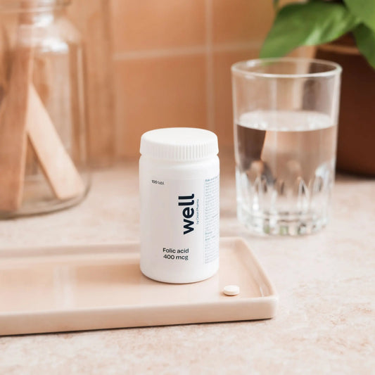 Well brand supplement bottle with a glass of water on a wooden surface