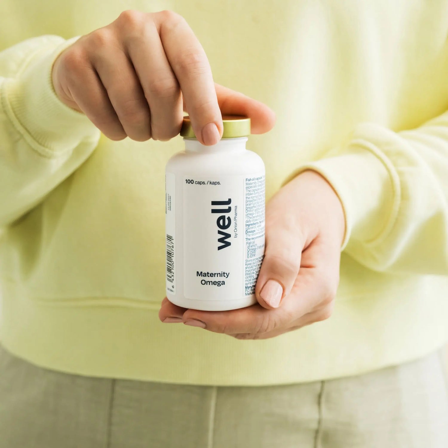 Person holding a supplement bottle labeled 'well' in a neutral setting