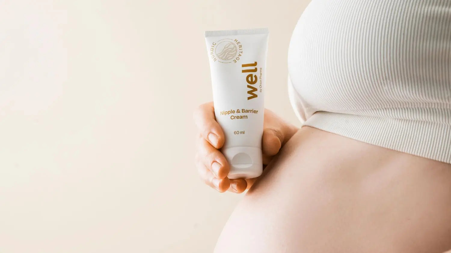 Hand holding a tube of Well by Orion Pharma Nipple & Barrier cream against a light background