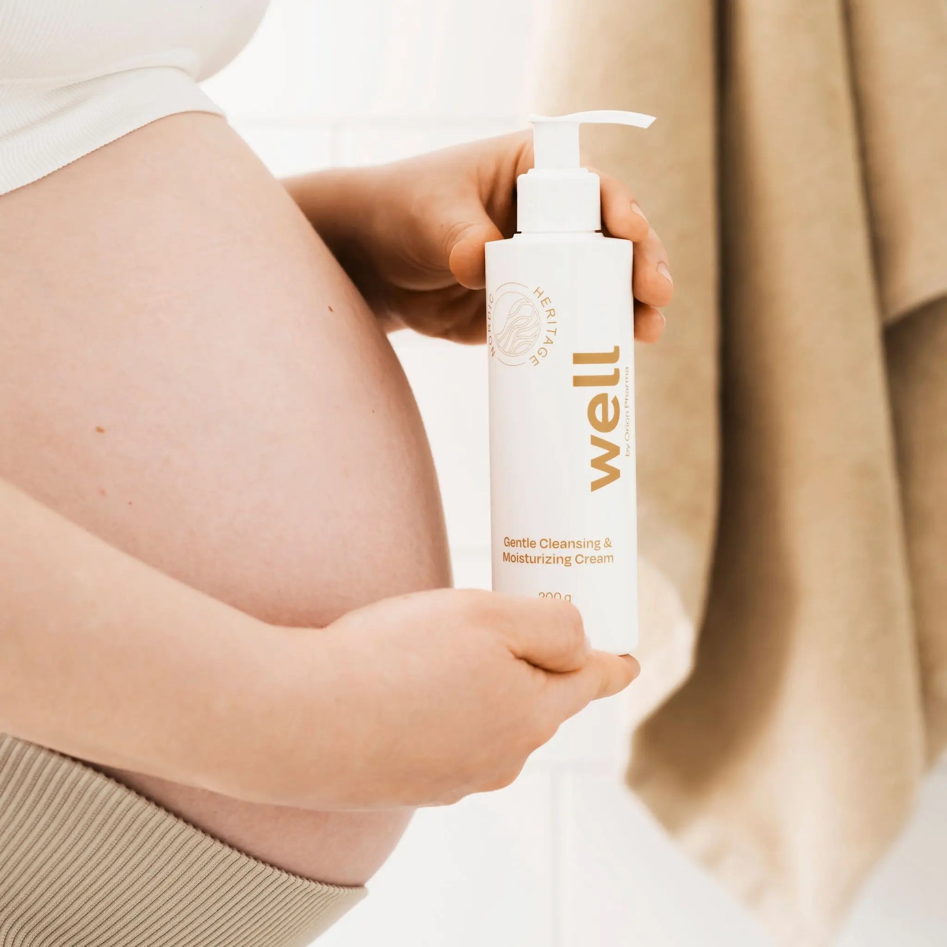 Person holding a bottle of Well by Orion Pharma skincare product with a neutral background