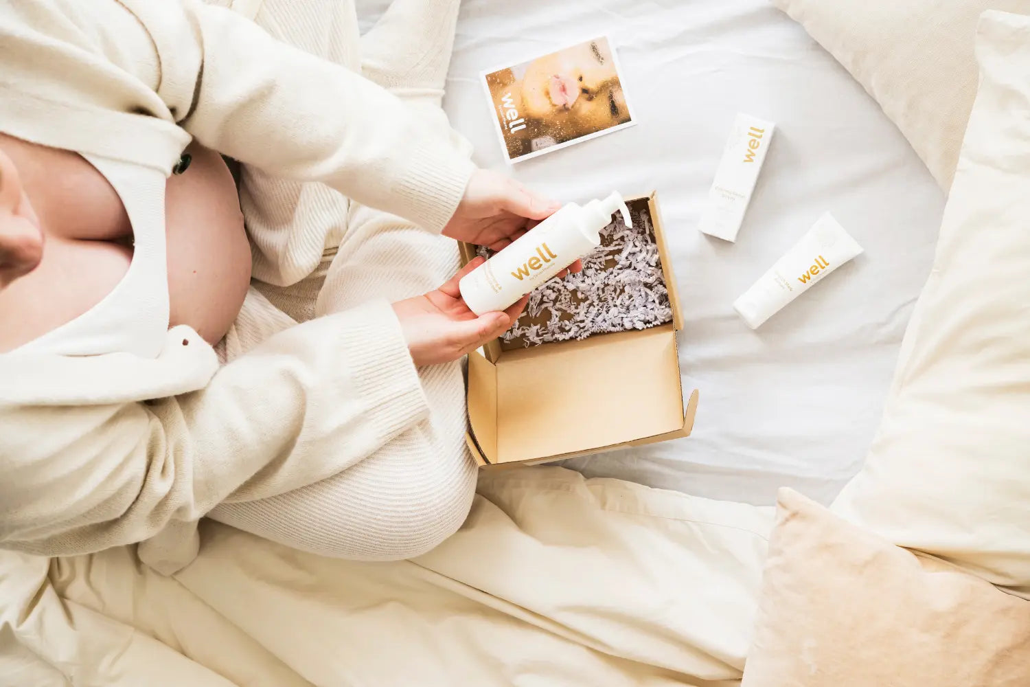 Person holding a box with skincare products on a bed