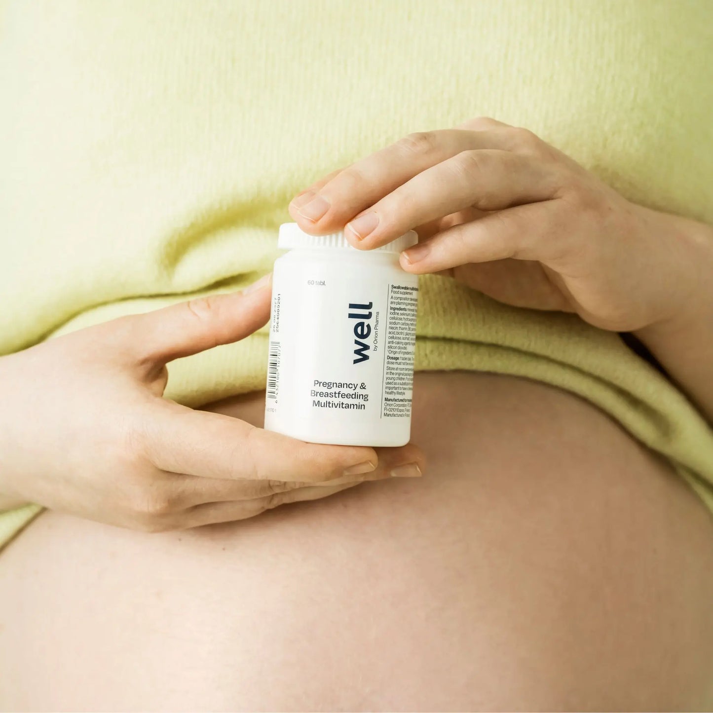 Person holding a Well by Orion Pharma pregnancy supplement container against a yellow background