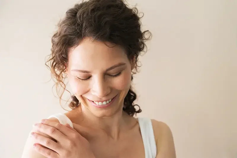Woman with curly hair smiling against a plain background