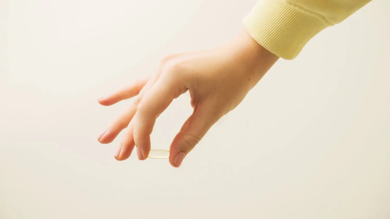 Hand holding omega tablet against a plain background