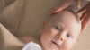Adult applying Well by Orion Pharma cream on baby and cuddling with baby.